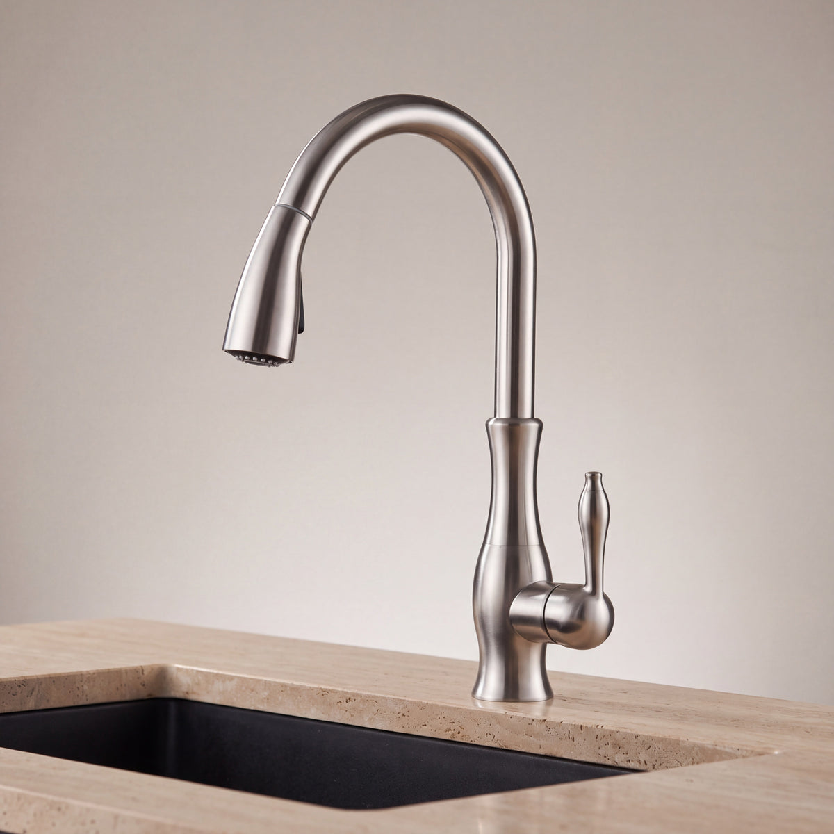 Mitigeur cuisine extractible LUCIANO en inox brossé installé sur un plan en travertin au-dessus d’un évier noir, mise en situation