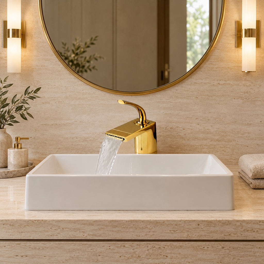 Mitigeur lavabo cascade doré AURELIO vu de face sous un miroir rond, plan en travertin, mise en situation