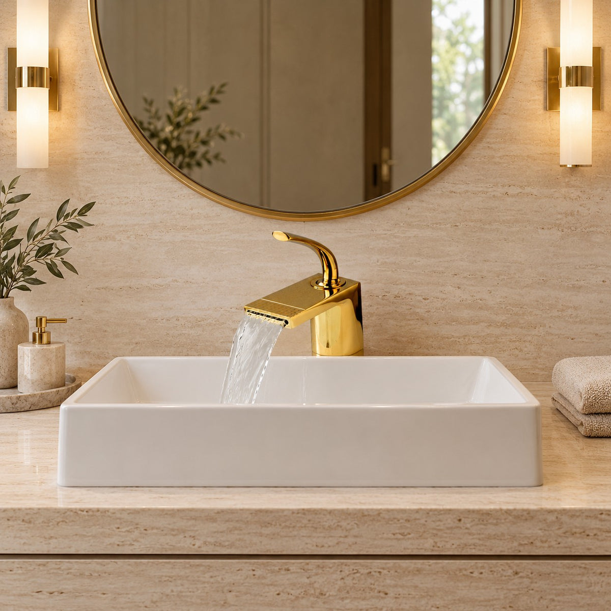 Mitigeur lavabo cascade doré AURELIO vu de face sous un miroir rond, plan en travertin, mise en situation