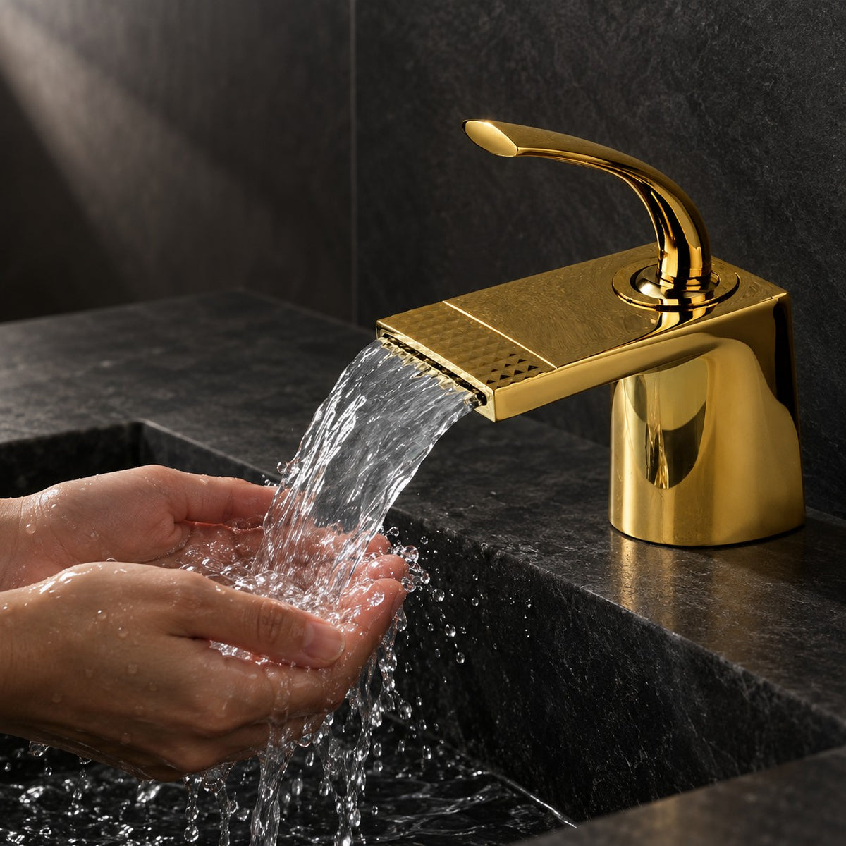 Mitigeur lavabo cascade doré AURELIO mains sous le jet, vasque en pierre noire, mise en situation