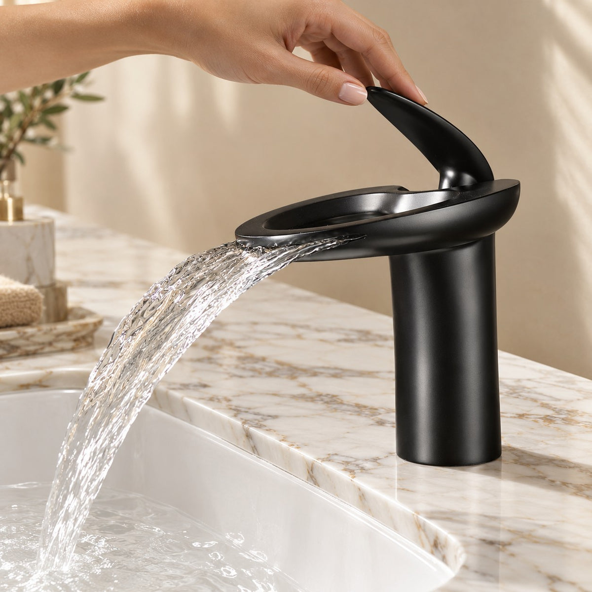 Mitigeur lavabo cascade NOVELLI avec une main sur la commande, plan en marbre, mise en situation