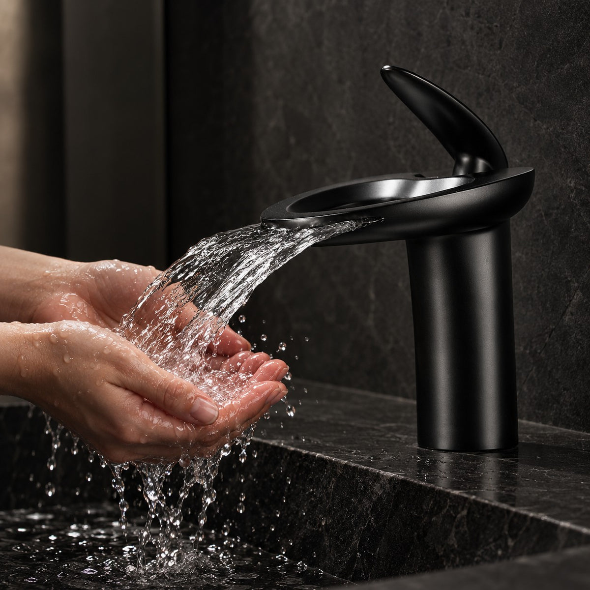 Mitigeur lavabo cascade NOVELLI mains sous le jet, vasque en pierre noire, mise en situation