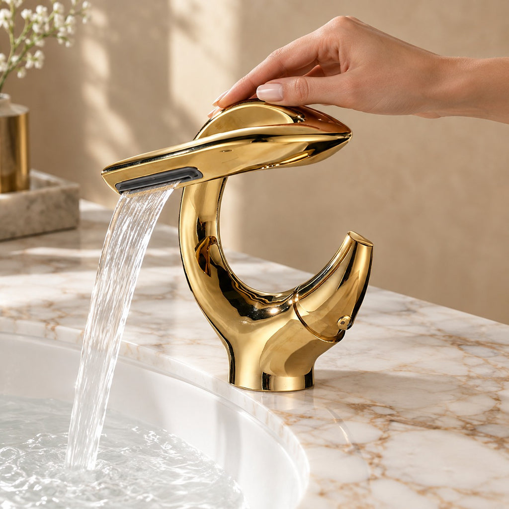 Mitigeur lavabo cascade sculptural OREZIO avec une main sur la commande, plan en marbre, mise en situation