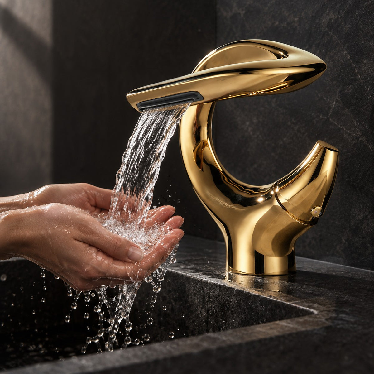 Mitigeur lavabo cascade sculptural OREZIO mains sous le jet, vasque en pierre noire, mise en situation