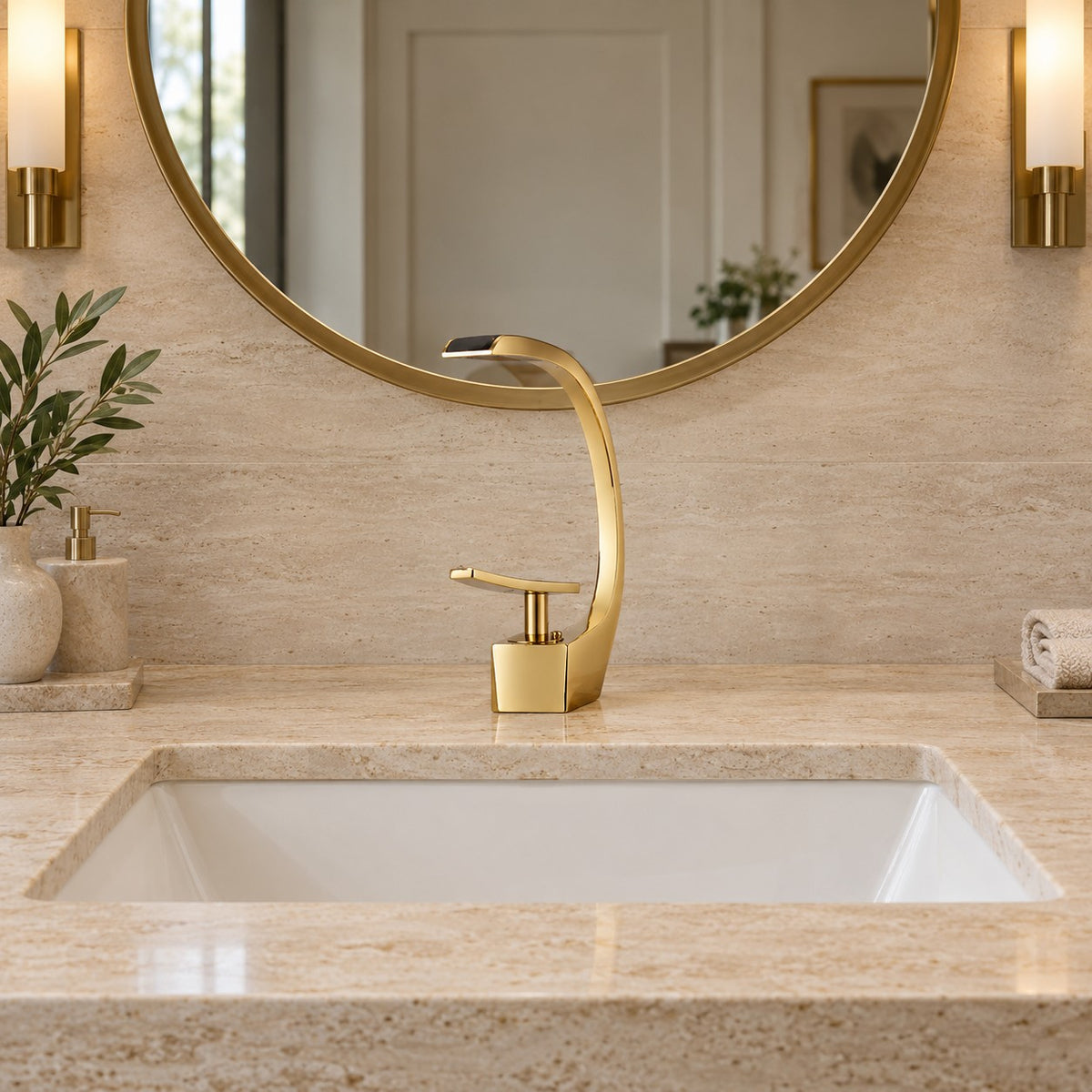 Mitigeur lavabo design courbé LUNAVIO doré vu de face sous un miroir rond, plan en travertin, mise en situation