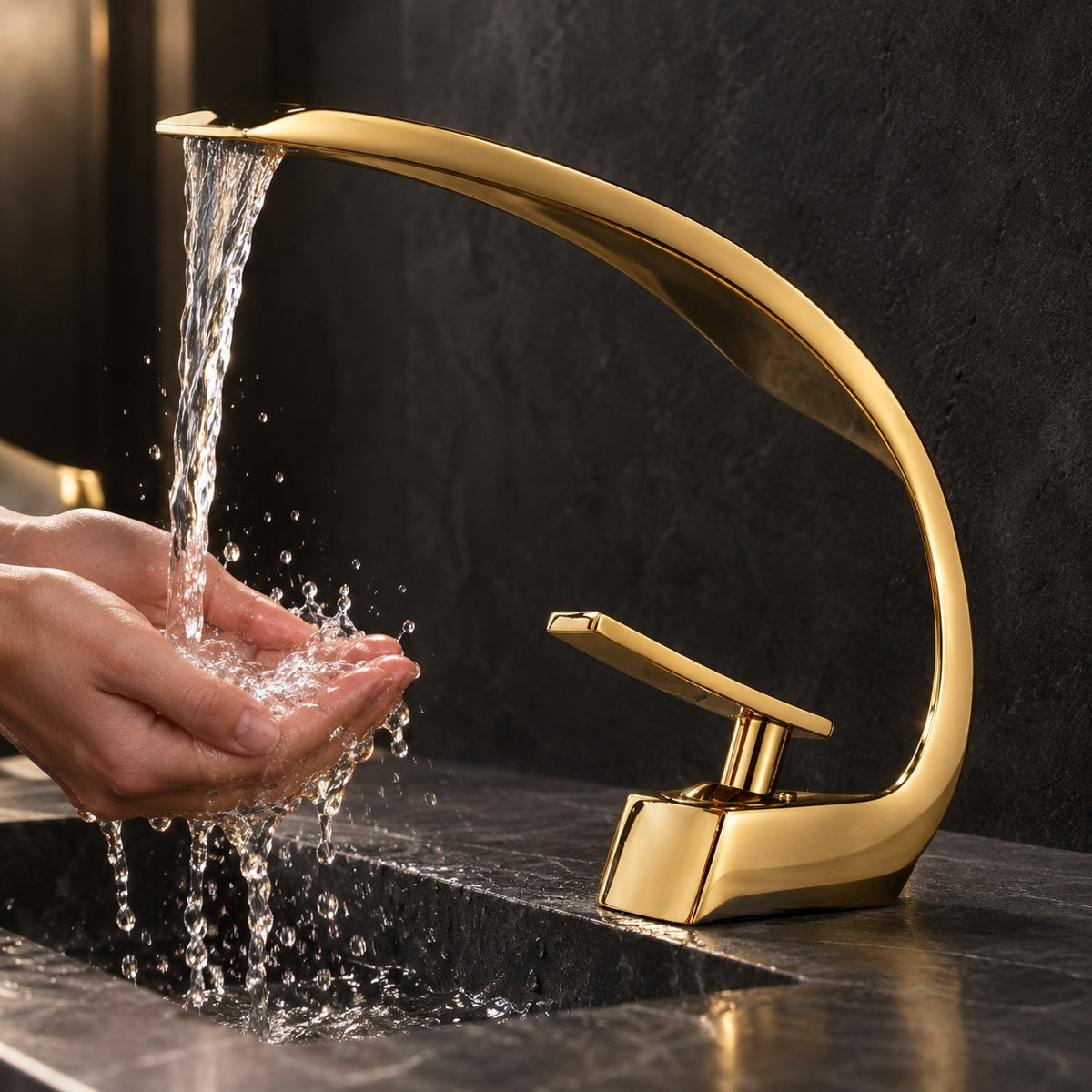 Mitigeur lavabo design courbé LUNAVIO doré mains sous le jet en cascade, vasque en pierre noire, mise en situation
