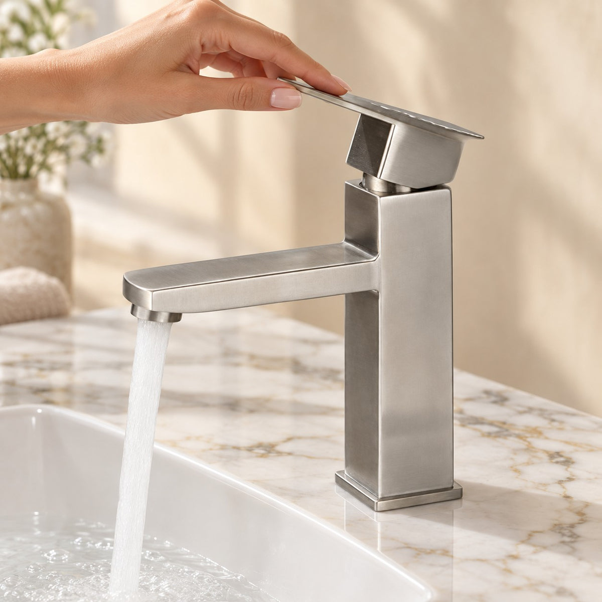 Mitigeur lavabo minimaliste VARESSI avec une main sur la commande, plan en marbre, mise en situation