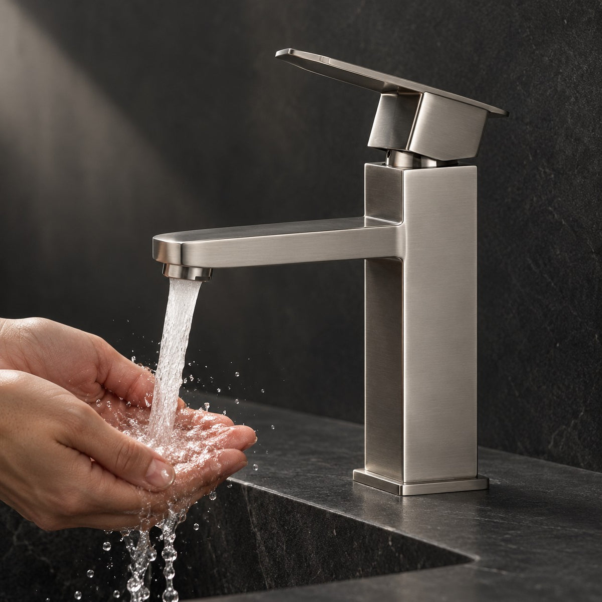Mitigeur lavabo minimaliste VARESSI mains sous le jet, vasque en pierre noire, mise en situation