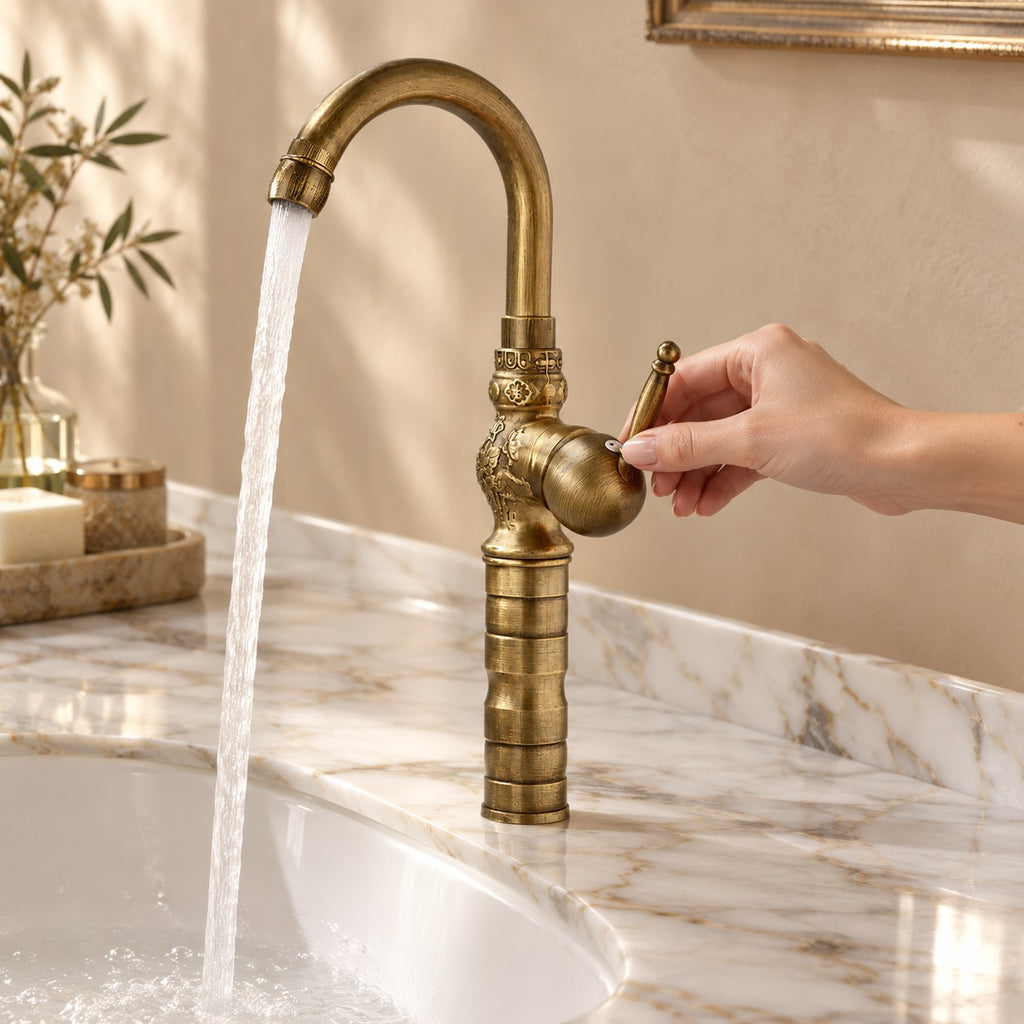 Robinet lavabo rétro en laiton FLORENZO avec une main sur la commande, plan en marbre, mise en situation