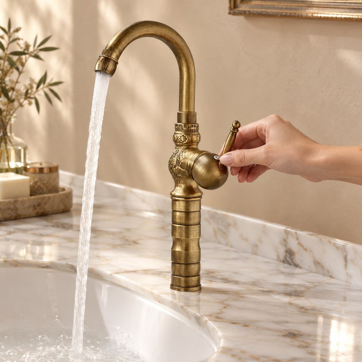 Robinet lavabo rétro en laiton FLORENZO avec une main sur la commande, plan en marbre, mise en situation