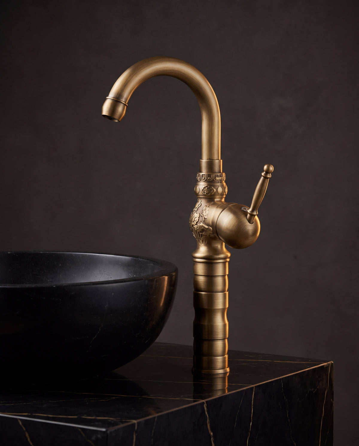 Robinet lavabo rétro en laiton FLORENZO à côté d’une vasque en pierre noire, mise en situation